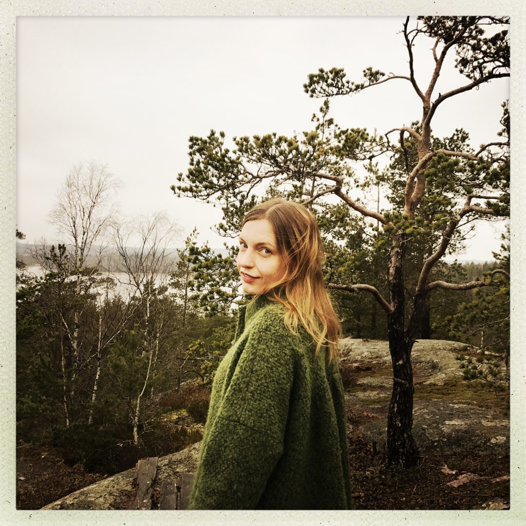 Laura Naukkarinen seisoo metsässä kalliolla